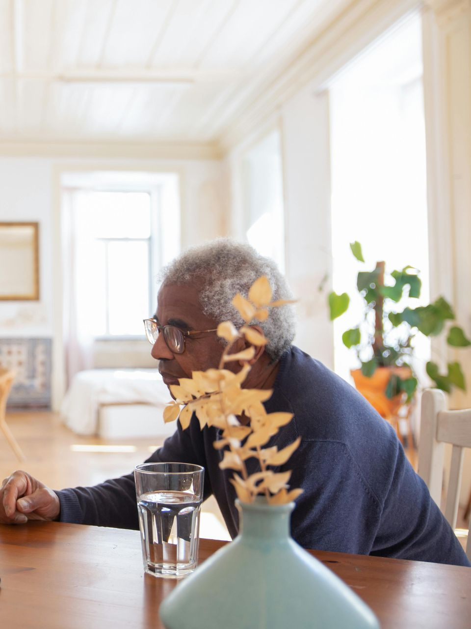 Older Black man in glasses sits at a wooden table. Elderly home care in Lancaster, CA.