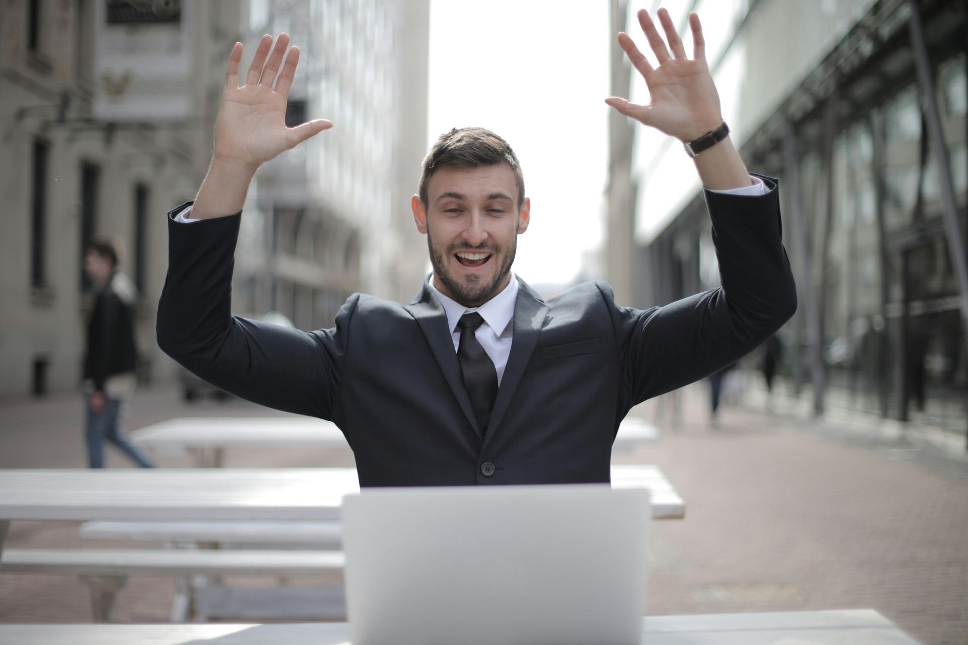 Man in suit with arms raised in excitement celebrating scholarship success
