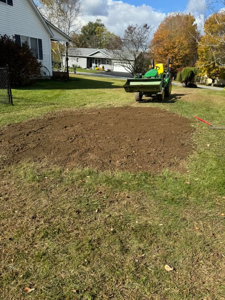 A green tractor is sitting on top of a lush green lawn next to a house.