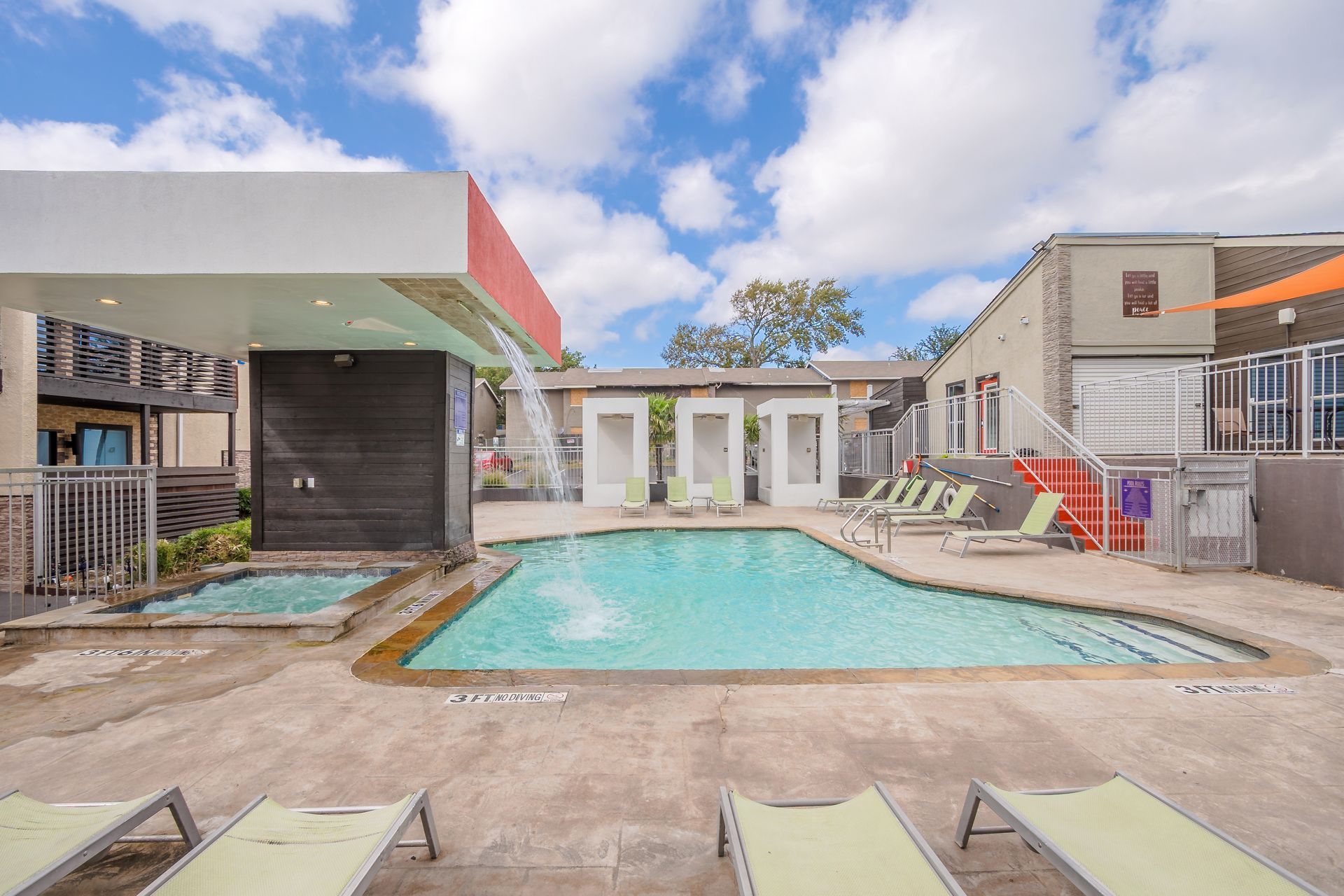 Photo of a community pool and jacuzzi, with a waterfall that pours into the pool
