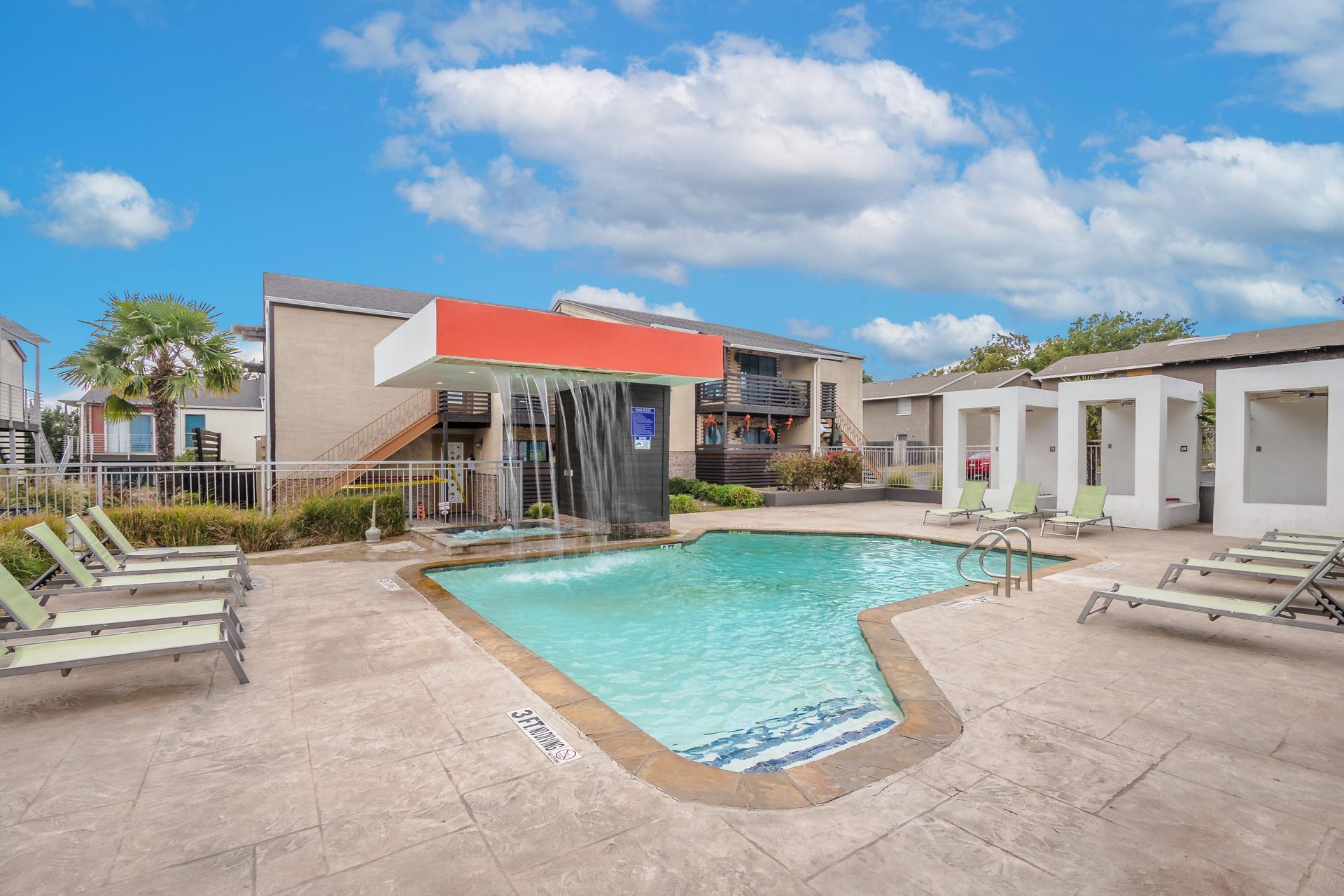 Photo of the community pool. It's a resort-style pool with a light waterfall that pours into the pool