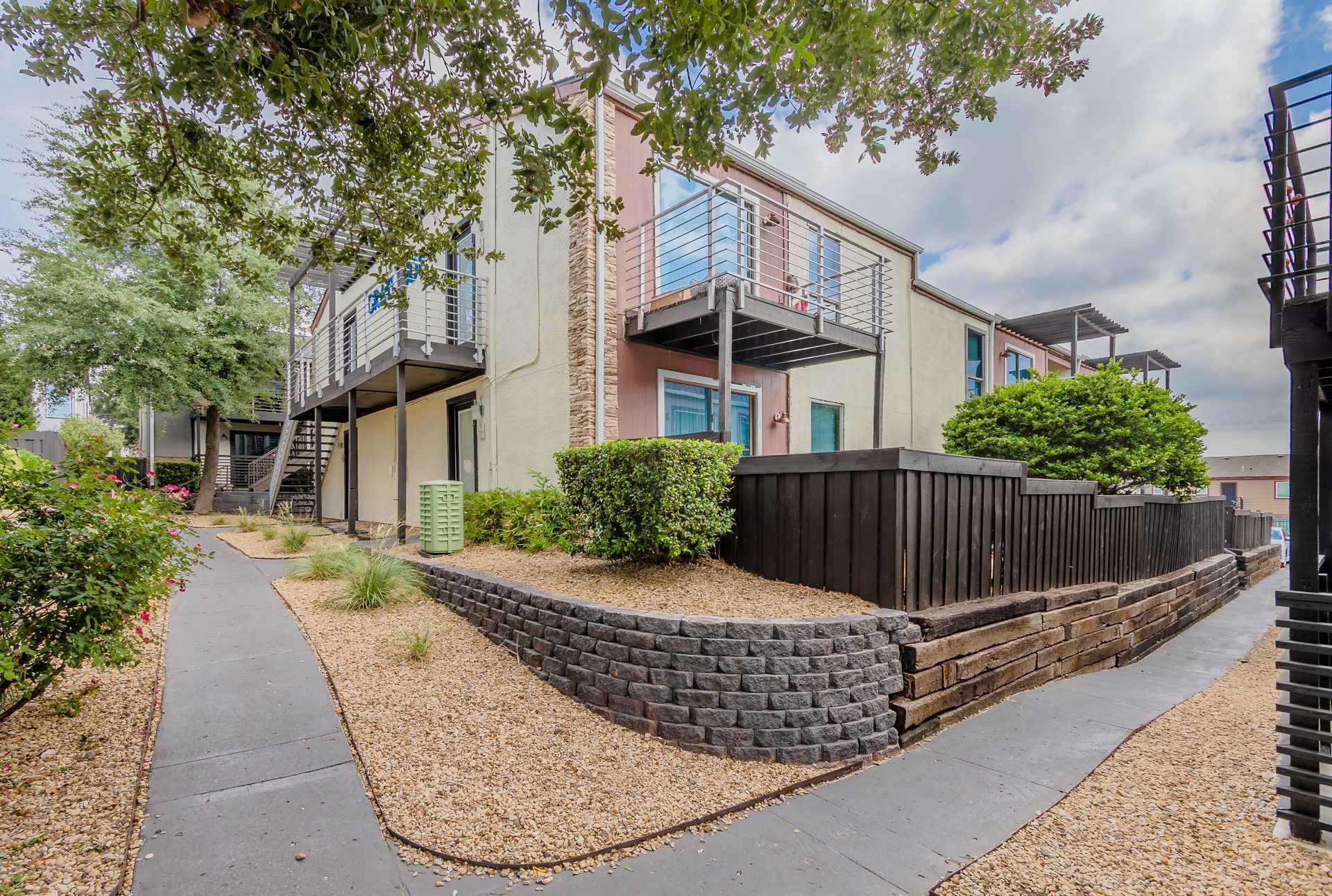 Photo of a two-story building, showing walkways and greenery around it