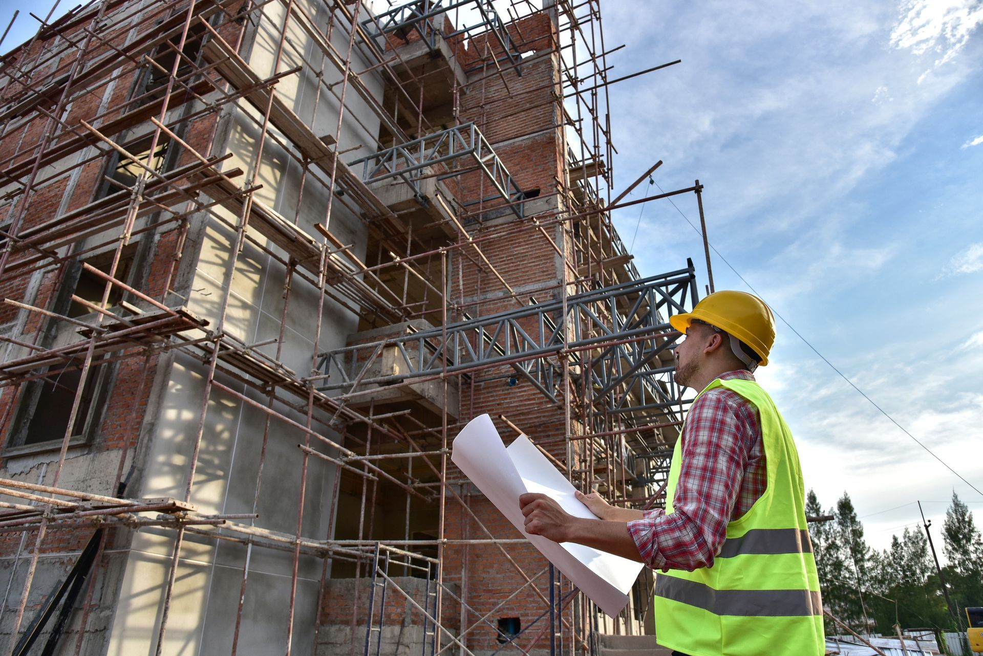 A construction worker is looking at a blueprint at a construction site.