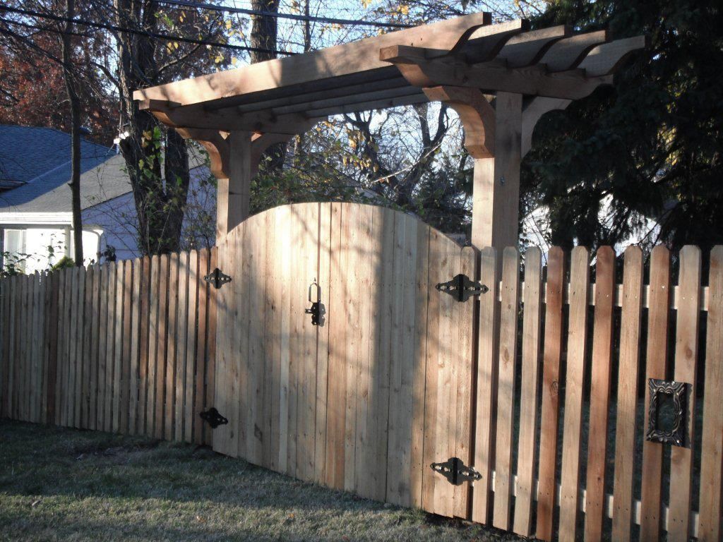 Wooden fence with arched gate and pergola.