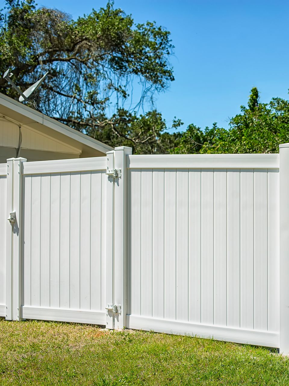 white vinyl fence corner enclosing a square area with vertical planks.
