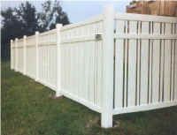 White vinyl fence in a grassy yard.