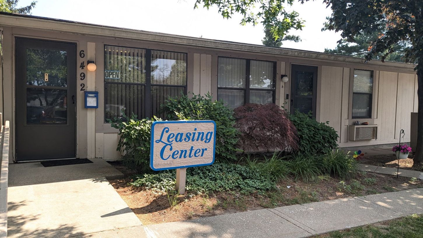 A white house with a blue sign that says leasing center