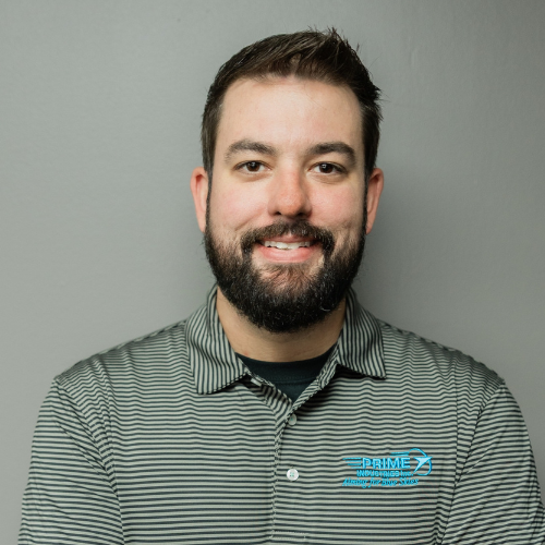 Man with a dark beard wearing a gray striped polo shirt, smiling at the camera against a gray background.