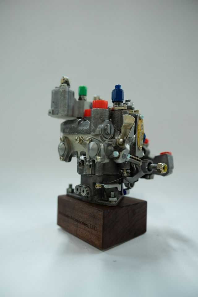 Small metallic engine model with colorful caps on a wooden base.