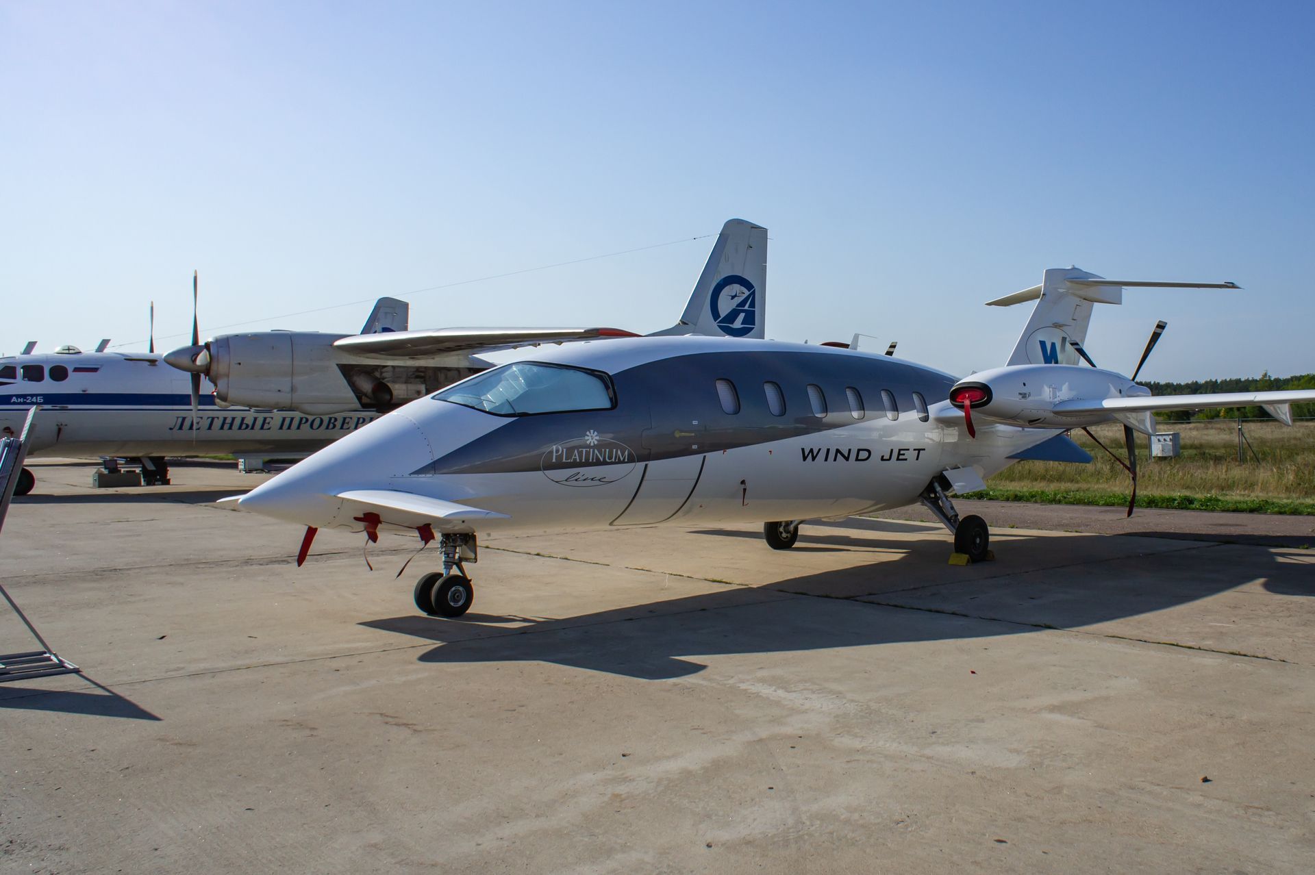White and gray turboprop Vivid Jet on tarmac with other aircraft in background.