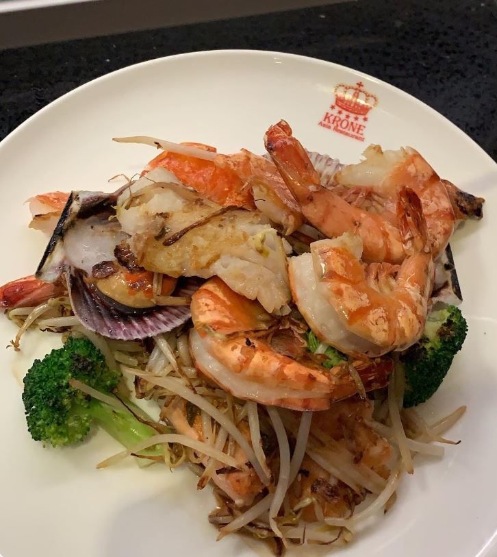 ein weißer Teller mit Garnelen und Gemüse auf einem Tisch