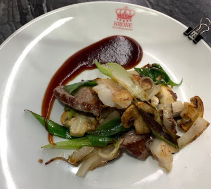 ein weißer teller mit fleisch und pilzen auf einem tisch