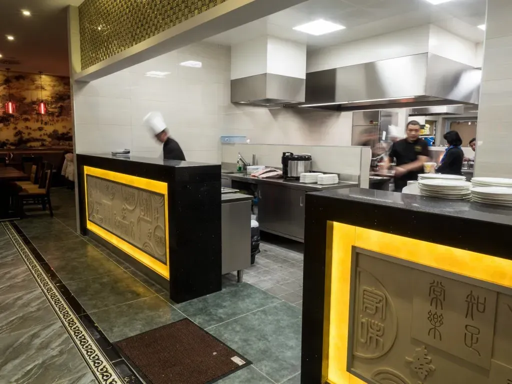 eine Küche in einem Restaurant mit einem Koch , der in der Küche steht .