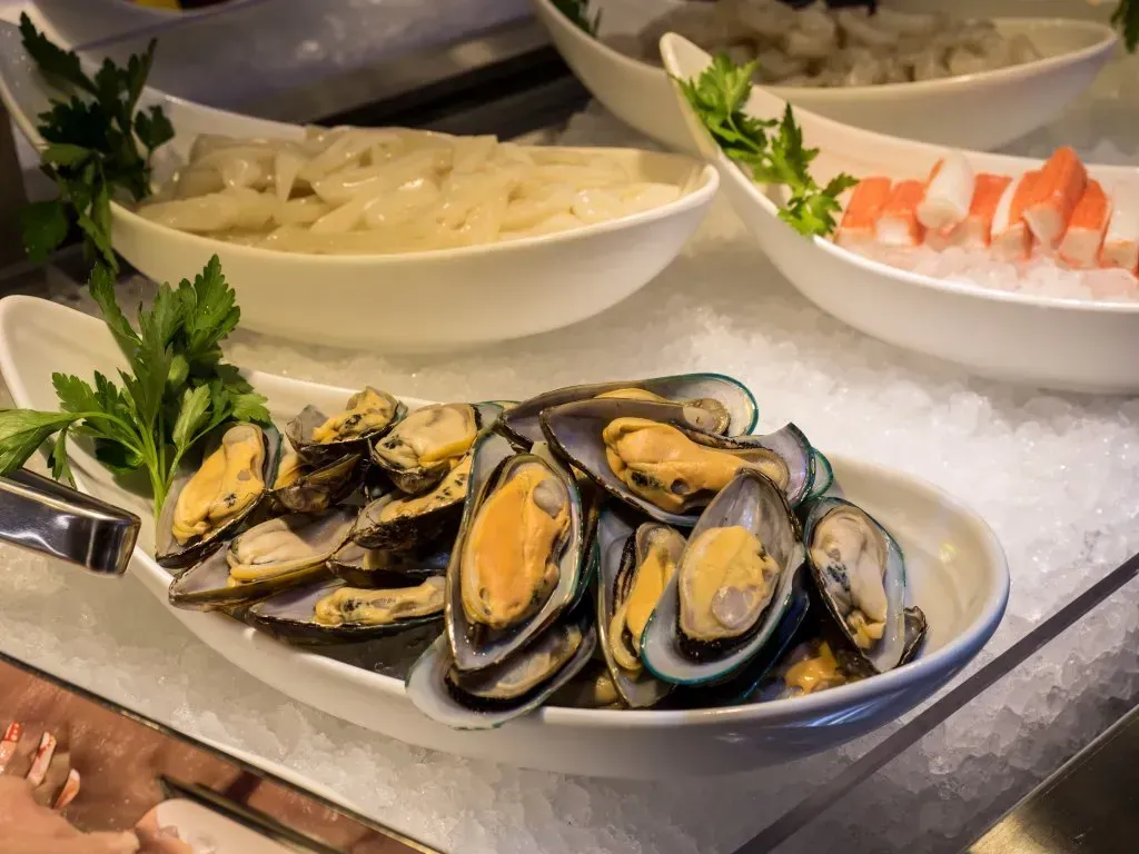 Auf einem Tisch steht ein Teller Muscheln auf Eis .