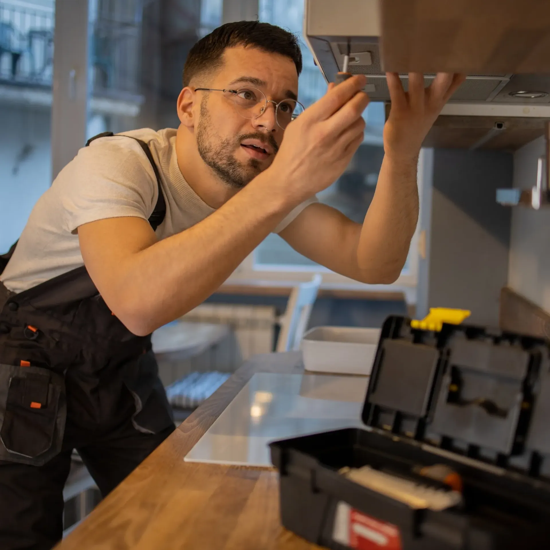 CK Maintenance - A man is working on a stove in a kitchen next to a toolbox.