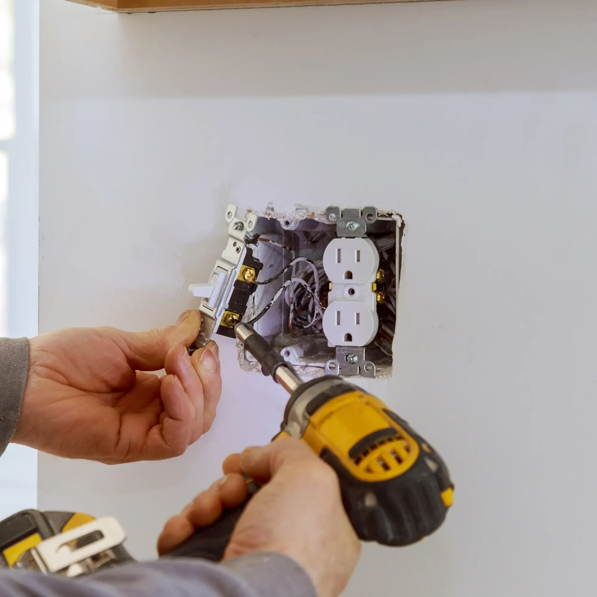 CK Maintenance - A man is using a dewalt drill to install an electrical outlet