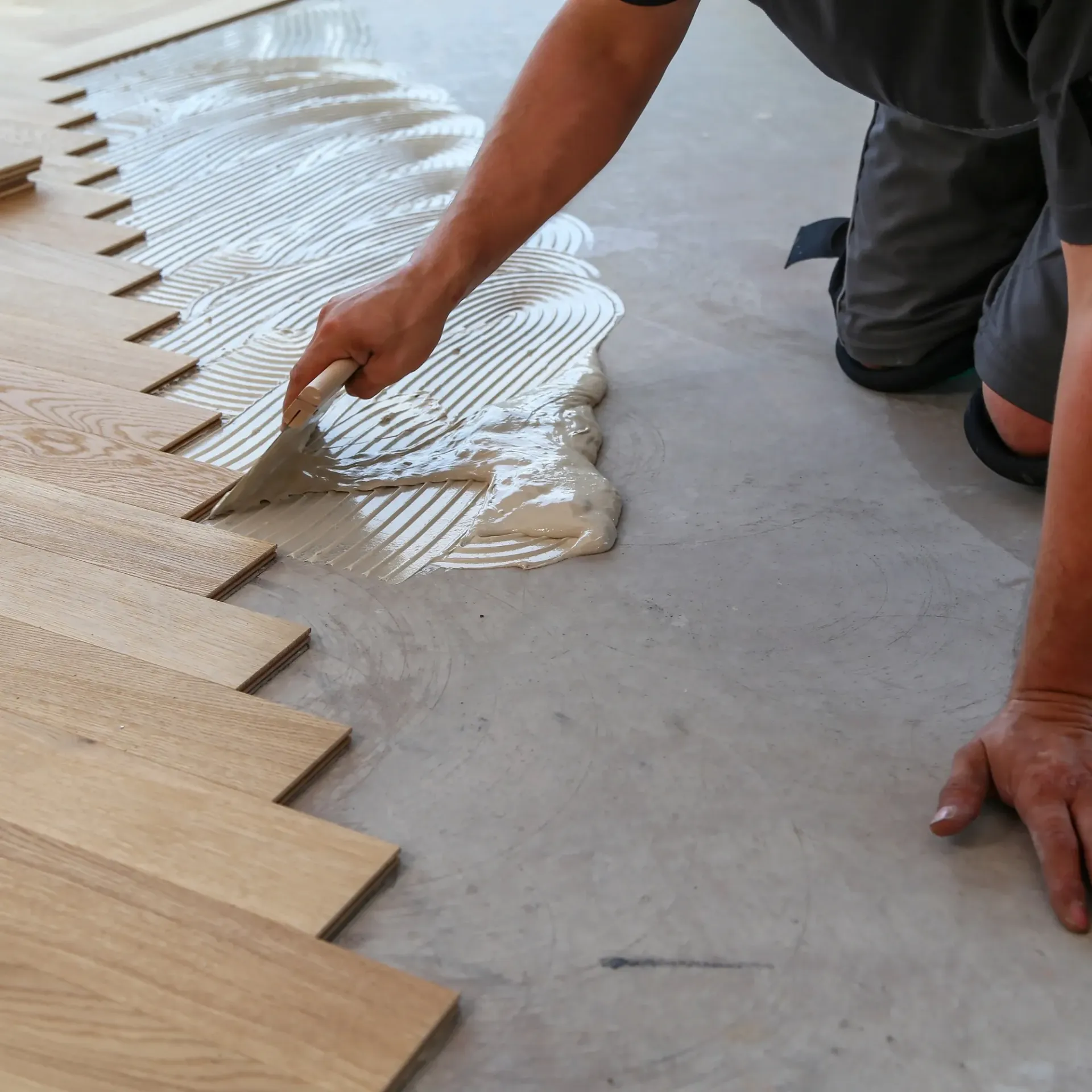 CK Maintenance - A person is applying glue to a wooden floor