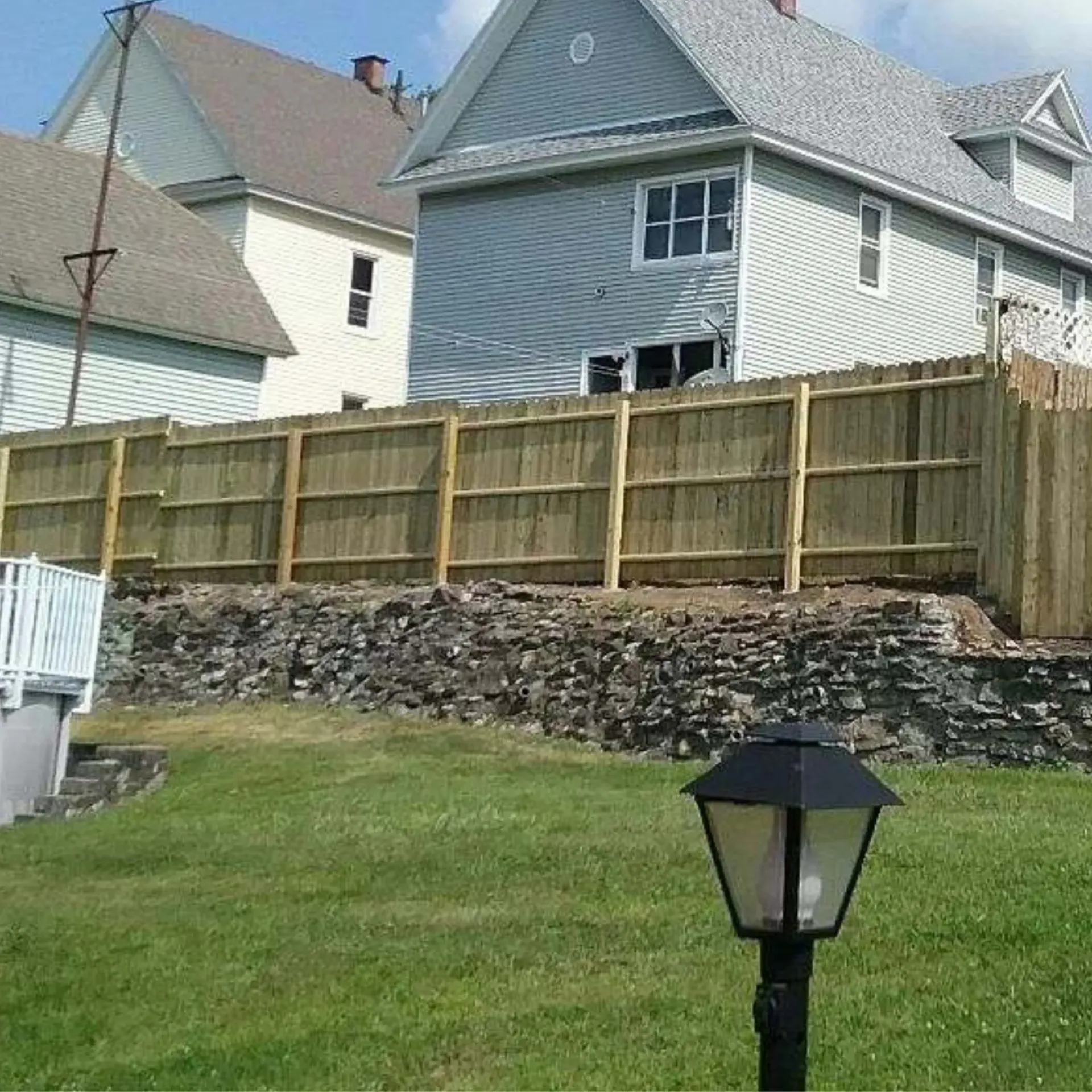 CK Maintenance LLC - A house with a wooden fence and a lamp post in front of it