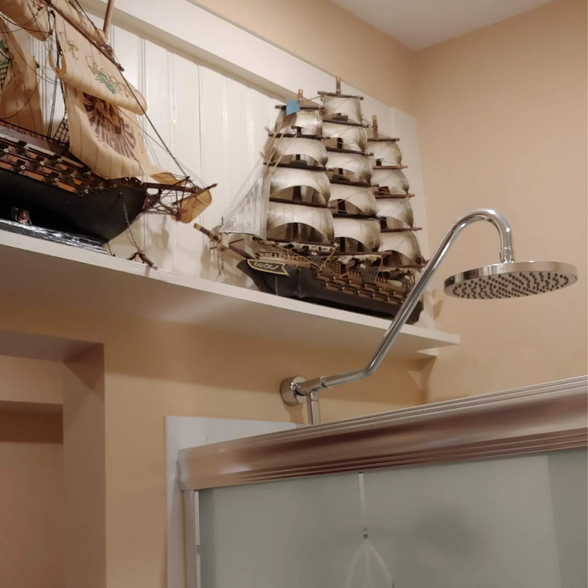 Ck Maintenance - A bathroom with a shower head and a model ship on a shelf
