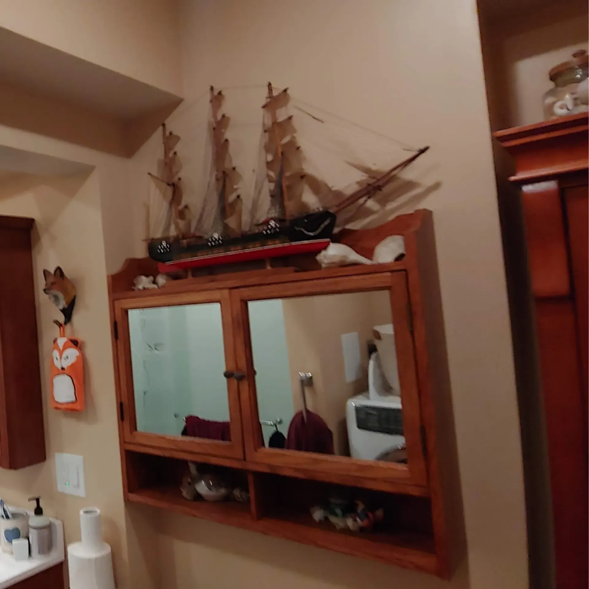 Ck Maintenance - A bathroom with a model ship on the wall above a mirror