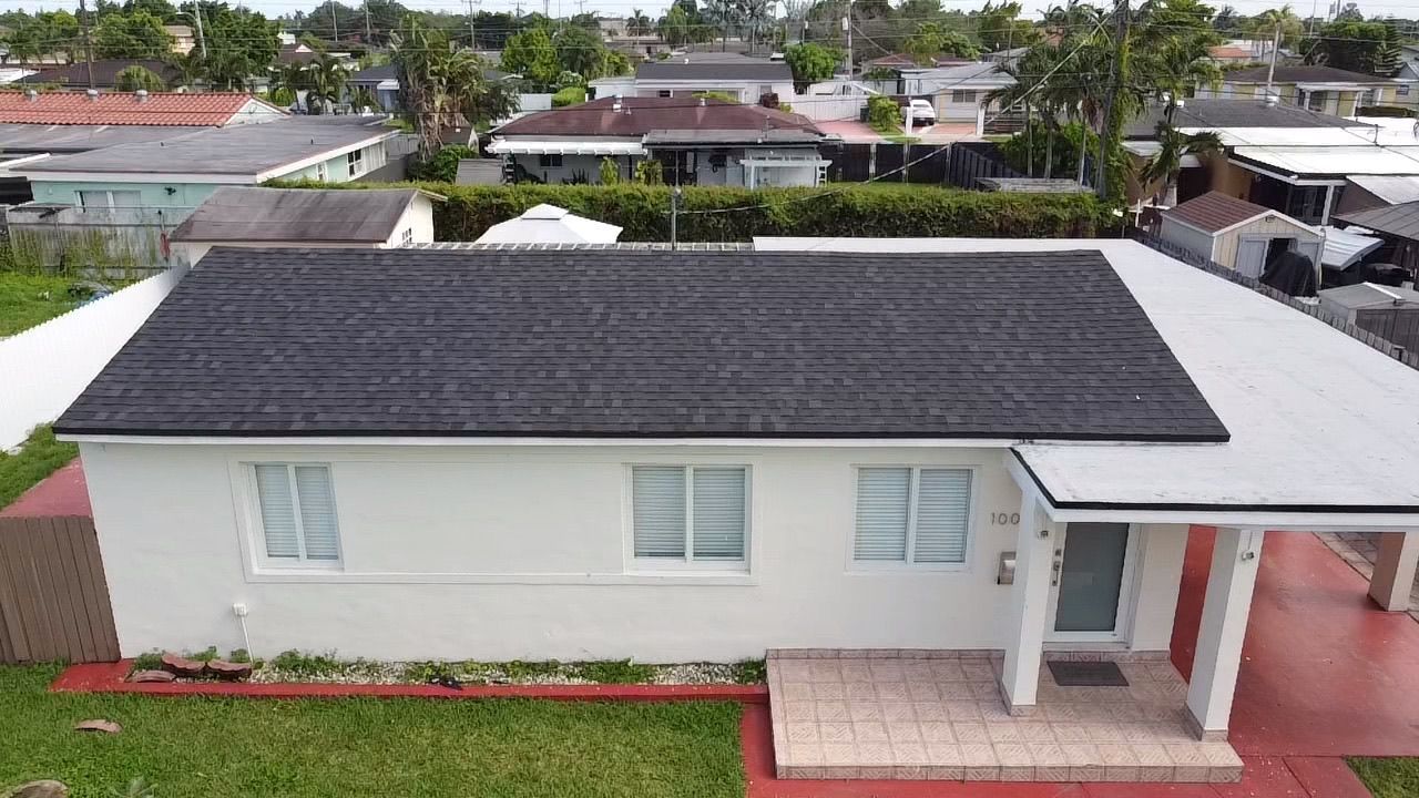 An aerial view of a white house with a black roof