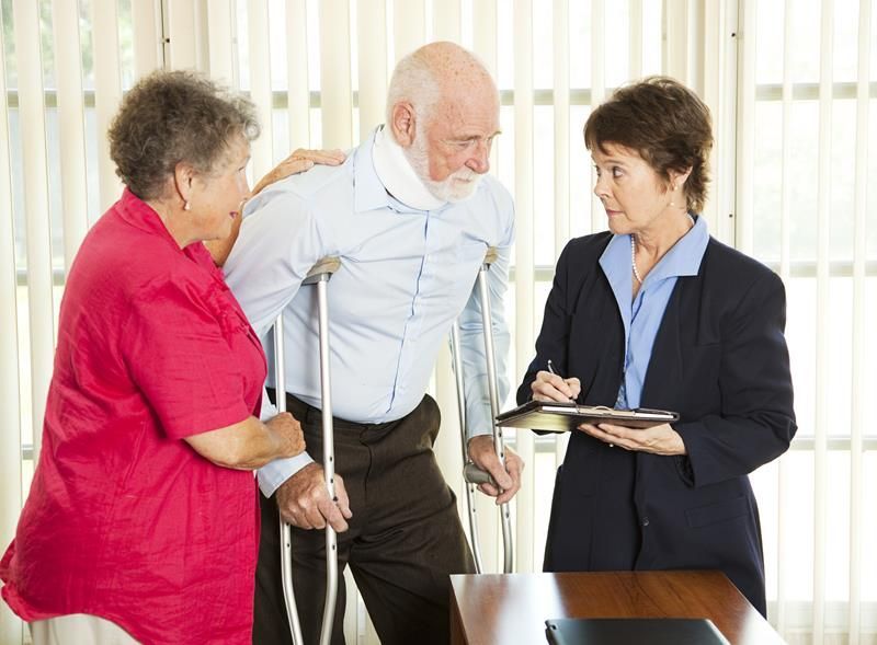 Man with neck brace and crutches, assisted by a woman, talking to a person in a suit who is holding a notepad.