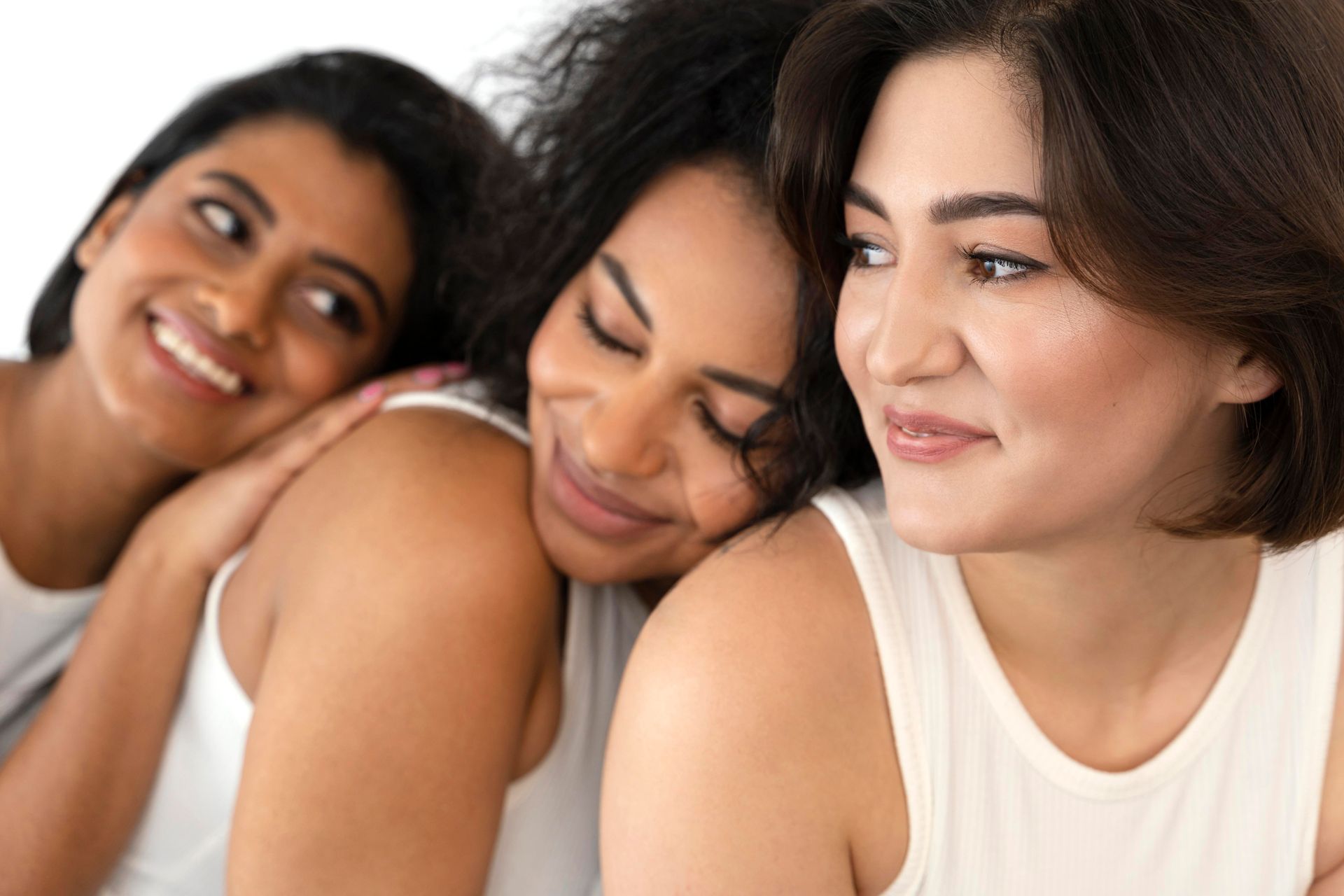 Three women after skincare session are sitting next to each other and smiling.