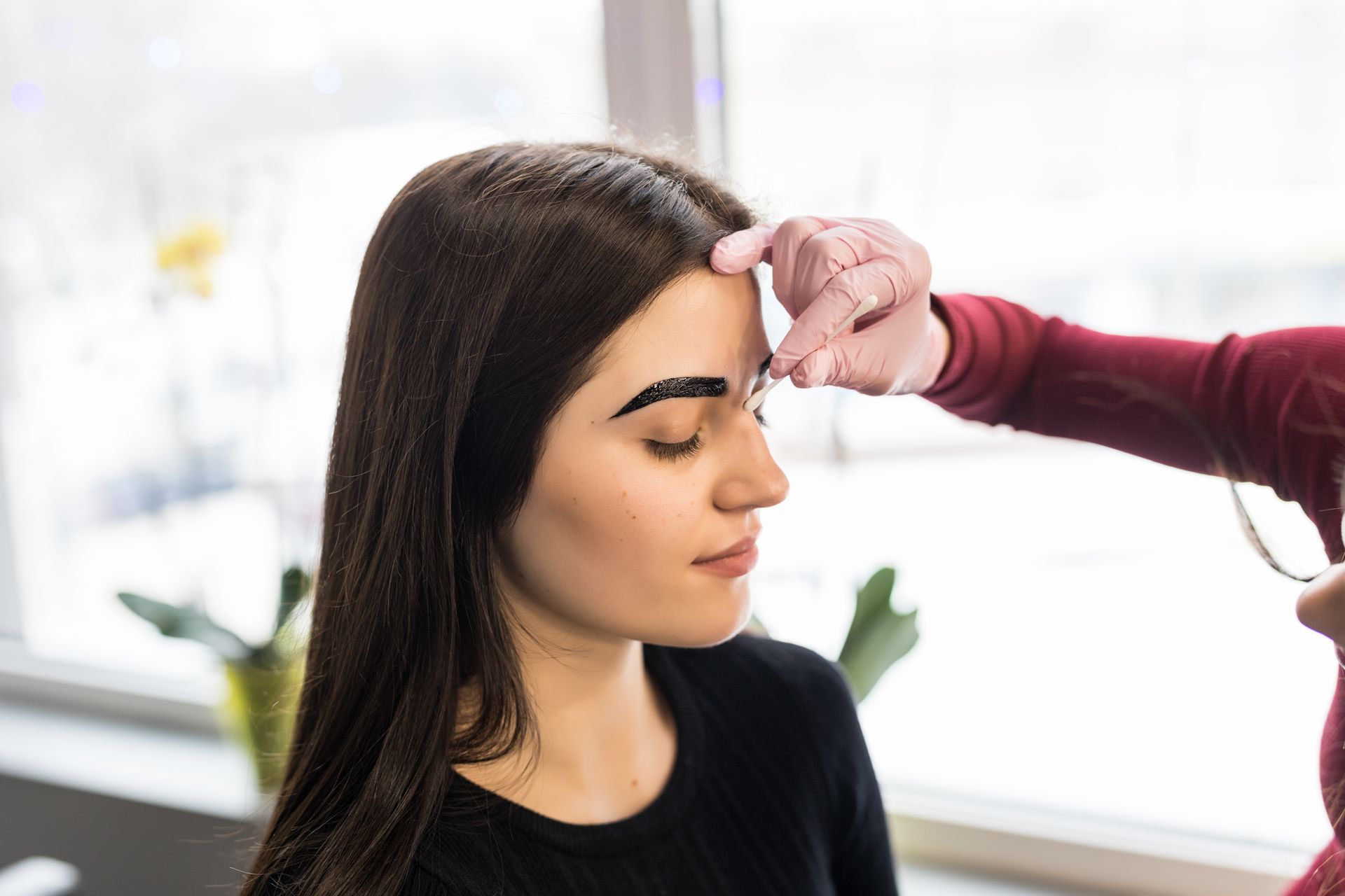 A woman is getting her eyebrows painted in a salon.