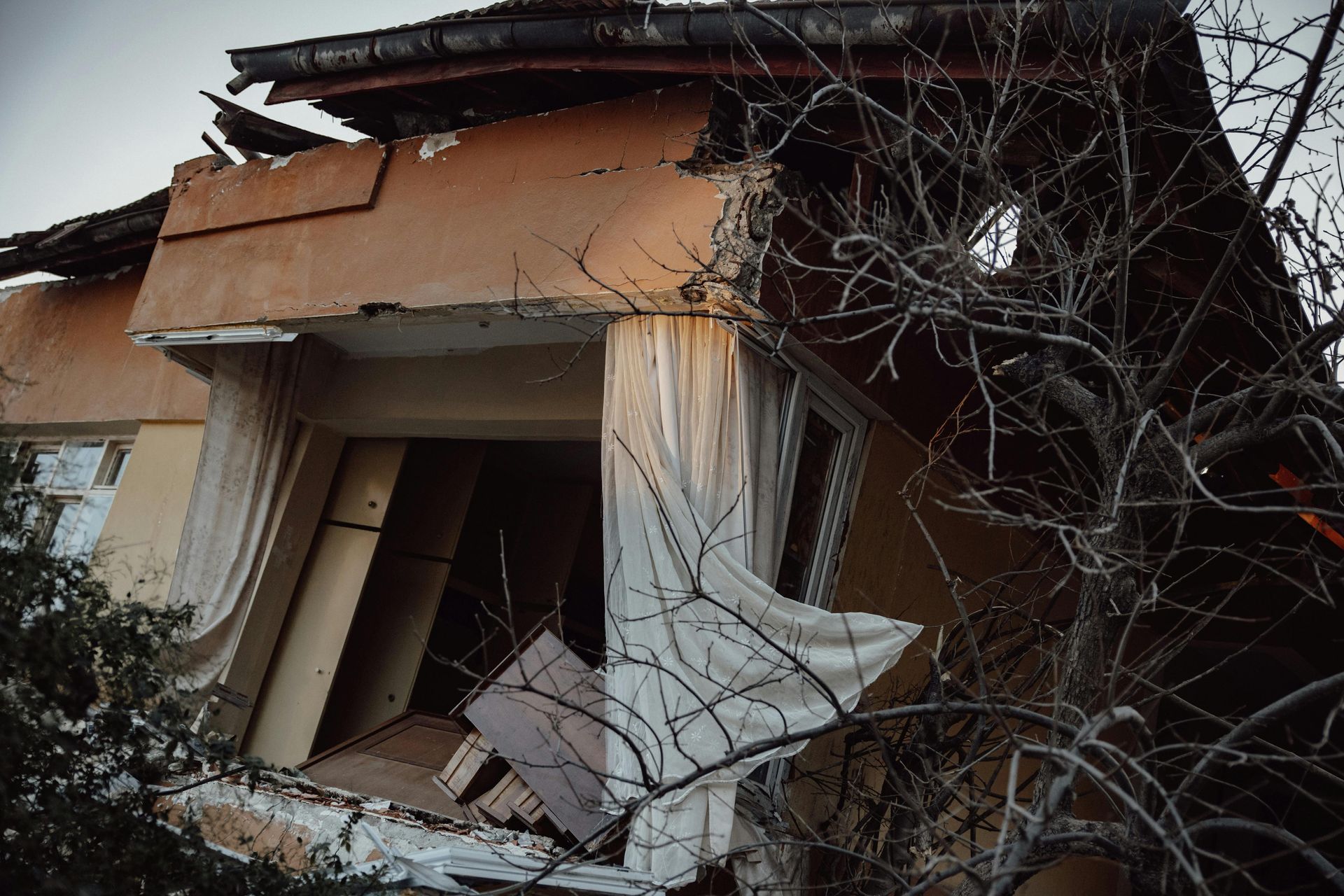 Damaged building facade with missing walls and exposed interior; daylight.