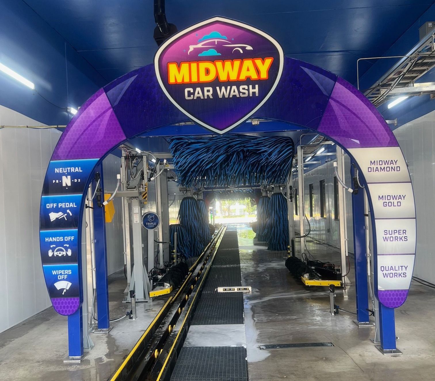 Midway Car Wash entrance with a blue and purple archway sign. Inside, a conveyor belt and car wash equipment are visible.