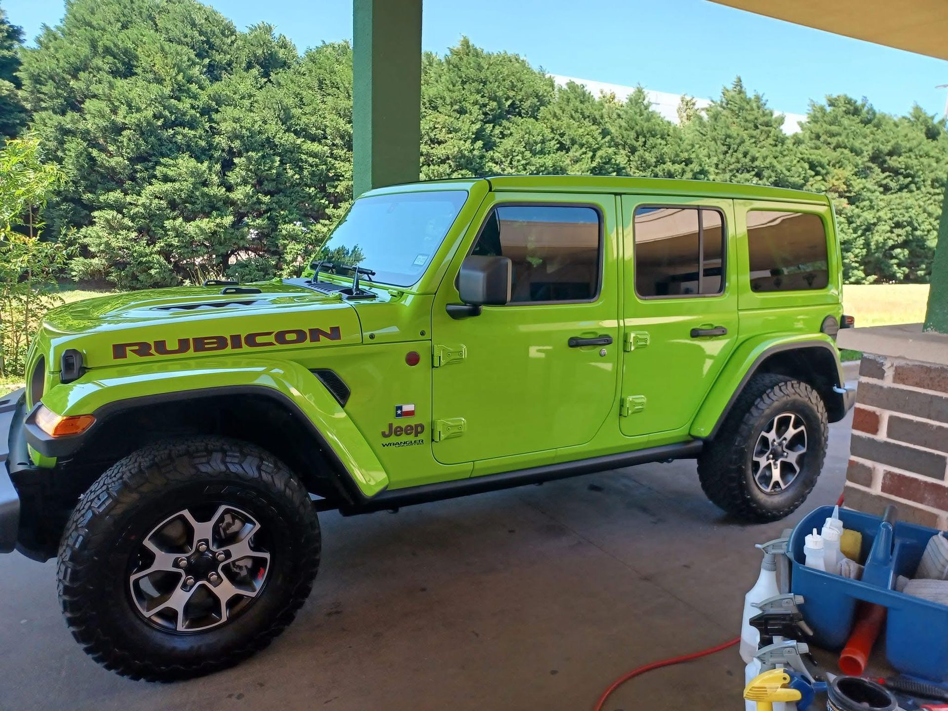 Lime green Jeep Wrangler Rubicon parked outside, with dark tinted windows, and black and silver wheels.