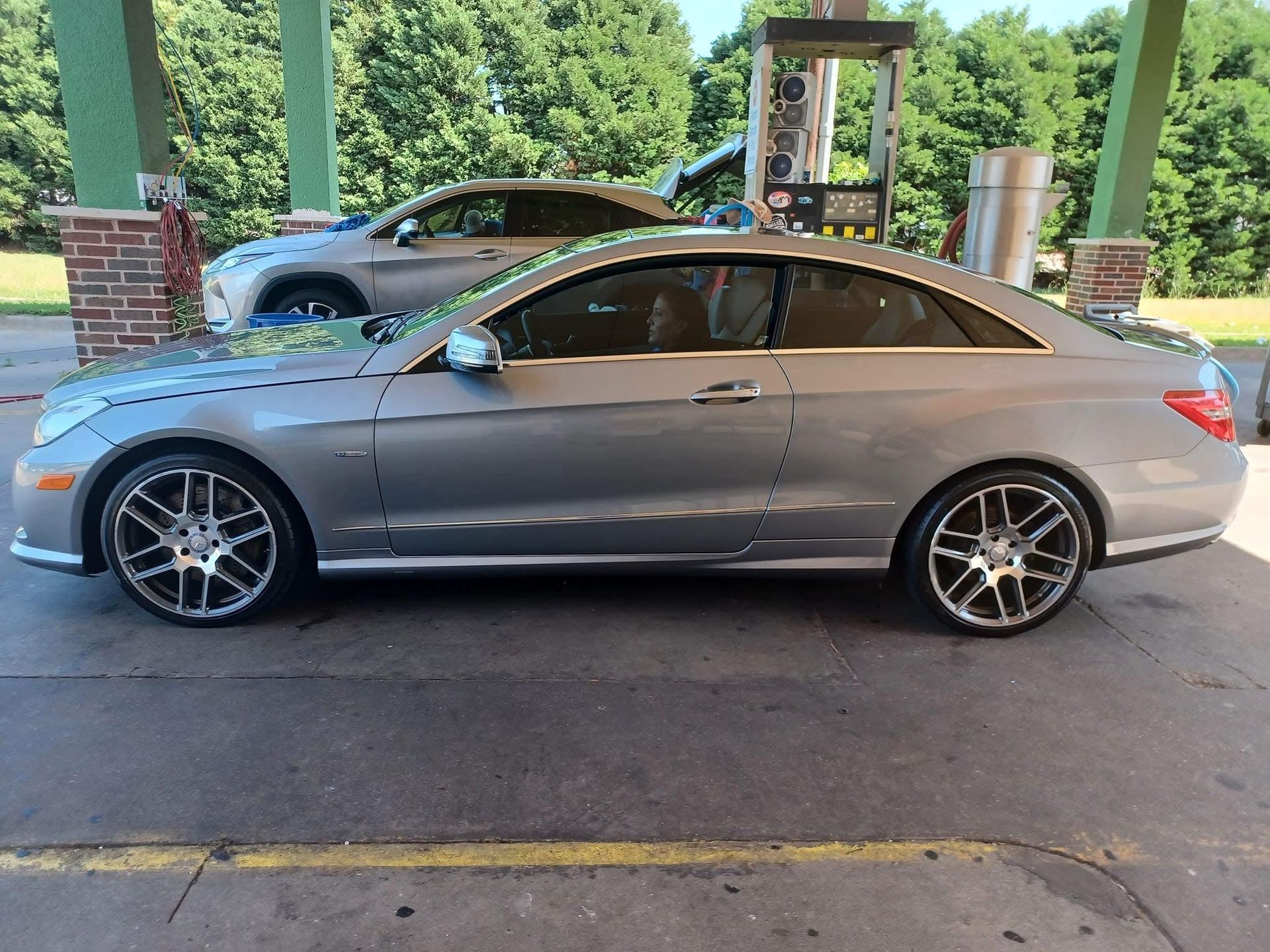 Silver Mercedes coupe parked at a gas station pump, other car in the background.