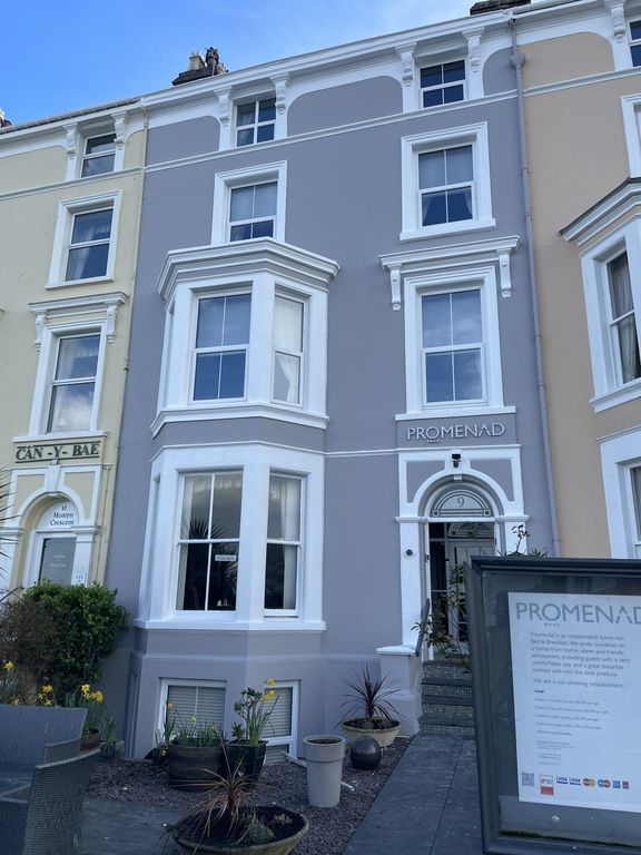 Gray Victorian building with white trim, arched doorway, and