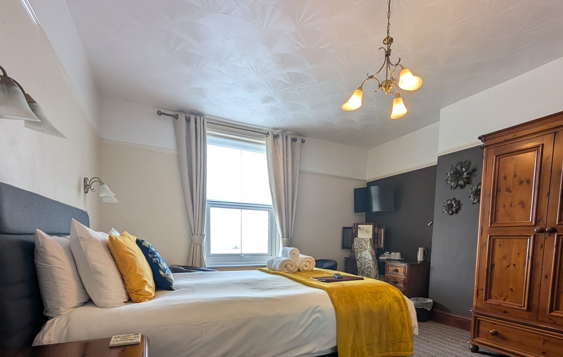 Bedroom with bed, wardrobe, window, and yellow accents.