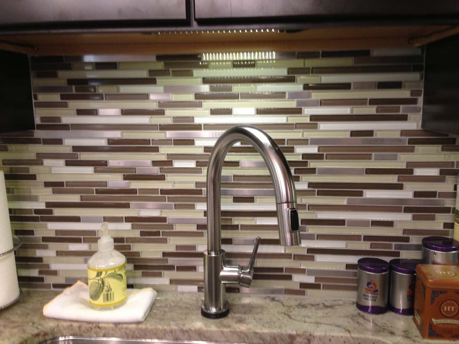 Kitchen faucet with a mosaic tile backsplash, sink, and countertop.