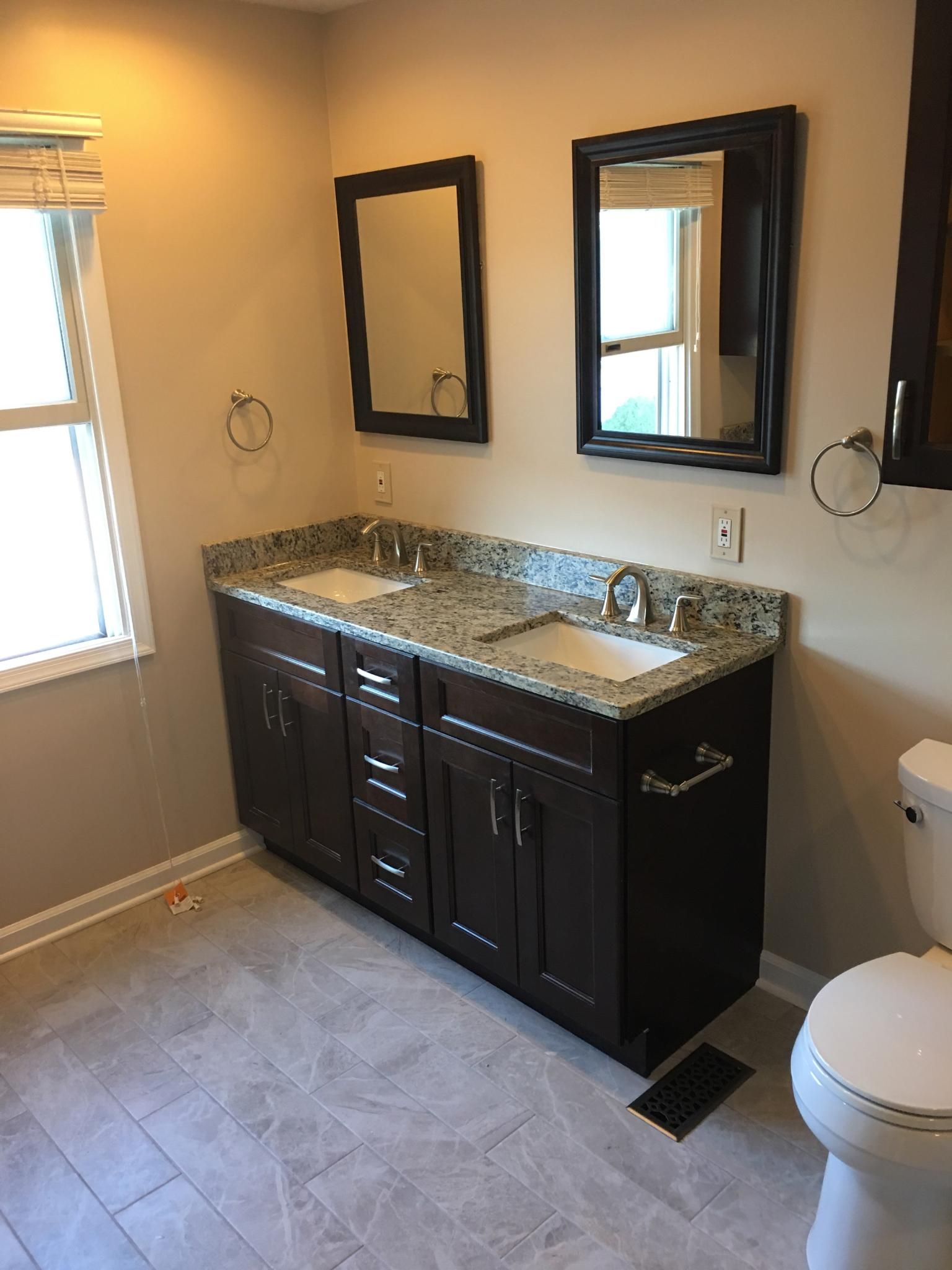 Bathroom with a dark brown double vanity, two mirrors, and a toilet.