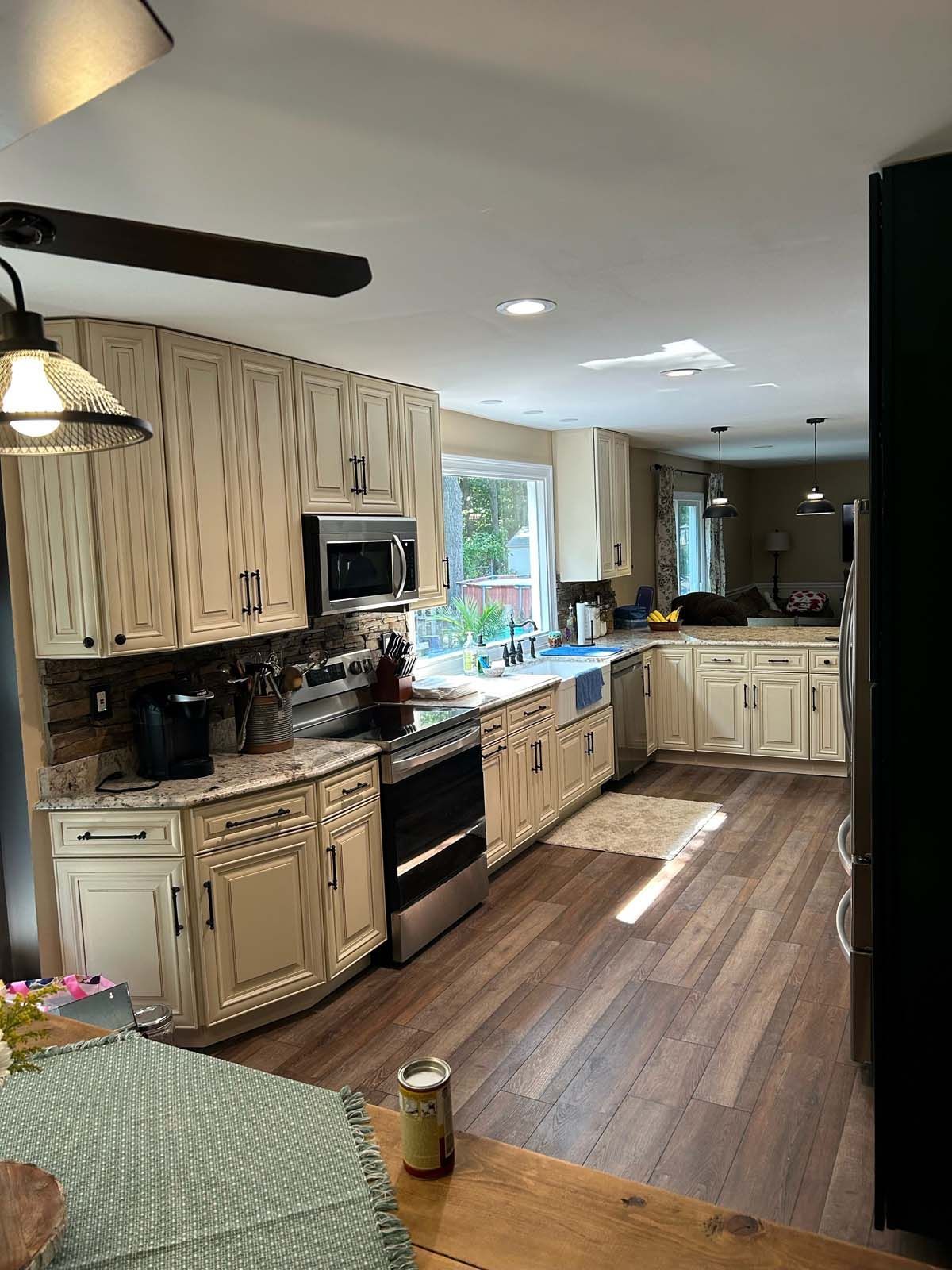 Beige kitchen with wood floors, stainless steel appliances, and white cabinets.