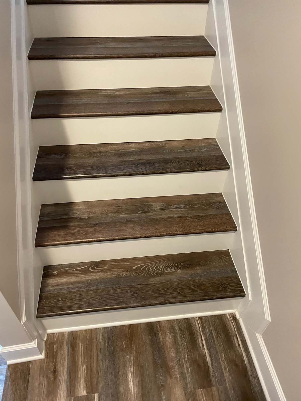 Wooden-looking steps with white risers. Flooring at the bottom matches the steps.