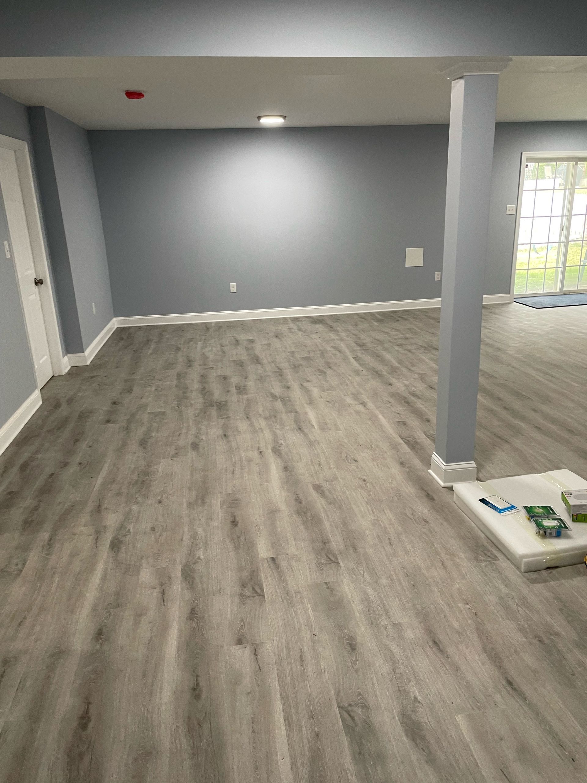 Empty room with gray walls, flooring, and white trim. A support beam is on the right.