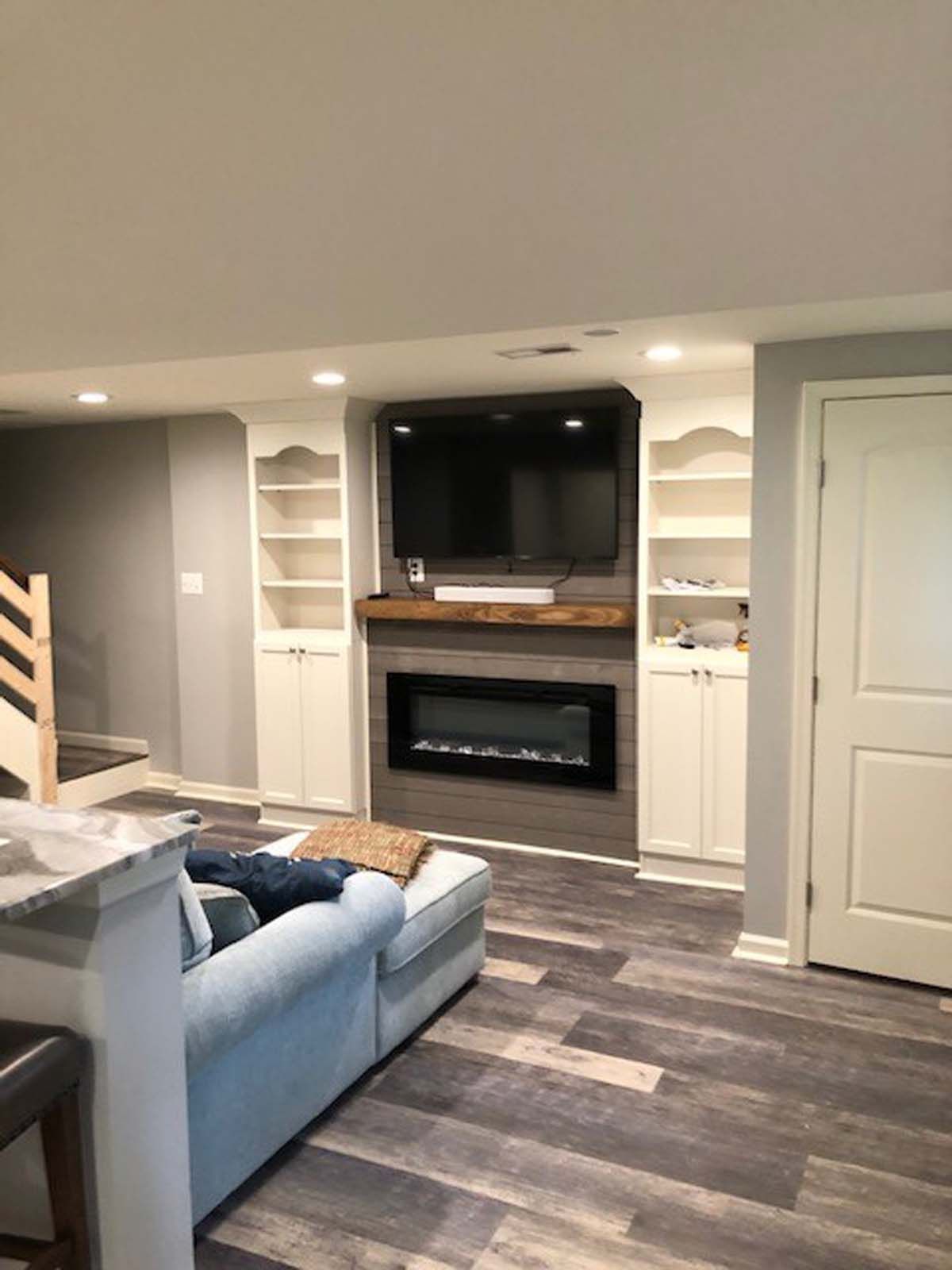 Living room with fireplace and built-in shelves; grey and white color scheme, TV mounted above fireplace.