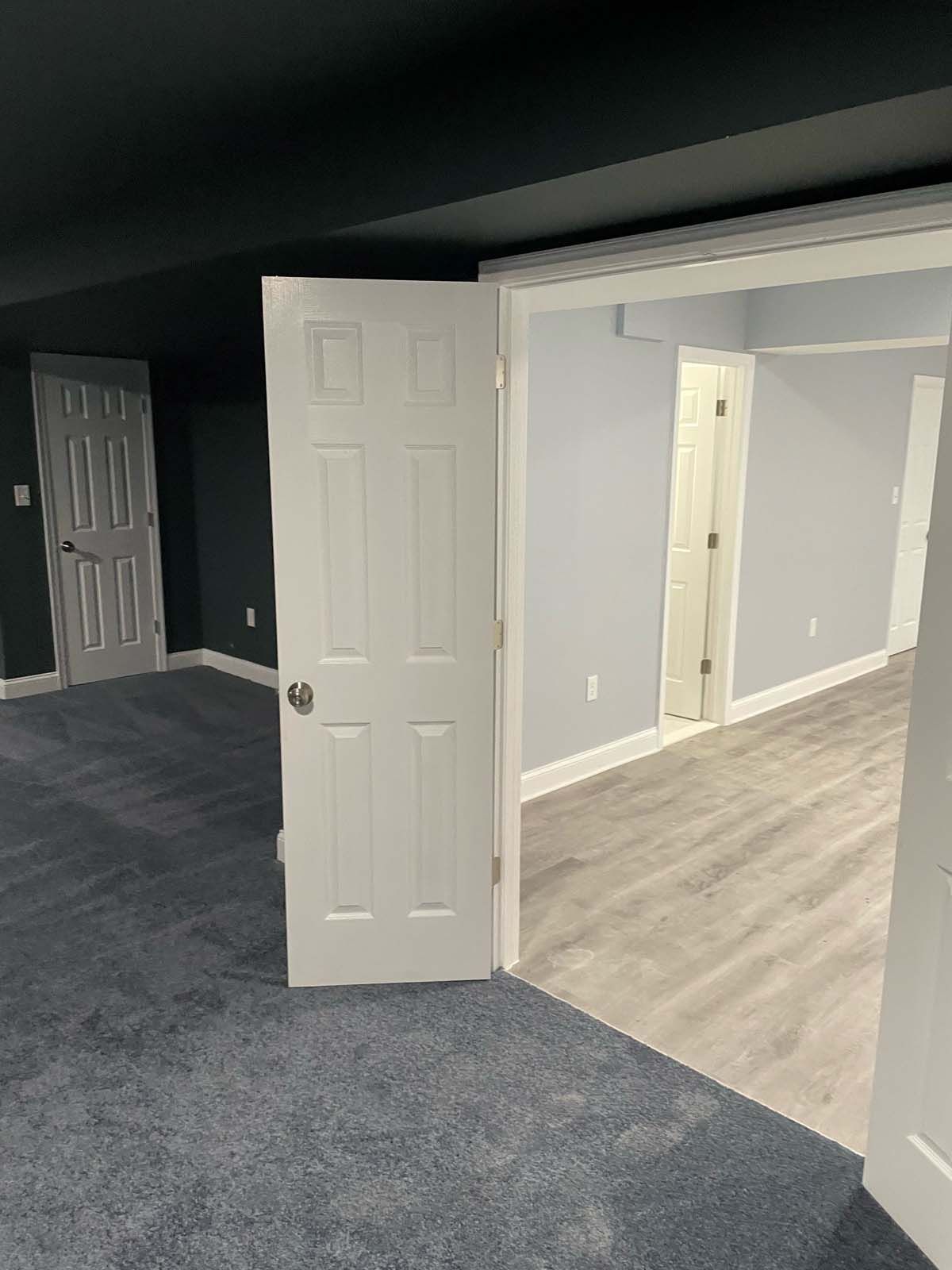 White doors open to carpeted and laminate-floored rooms with gray and blue walls.
