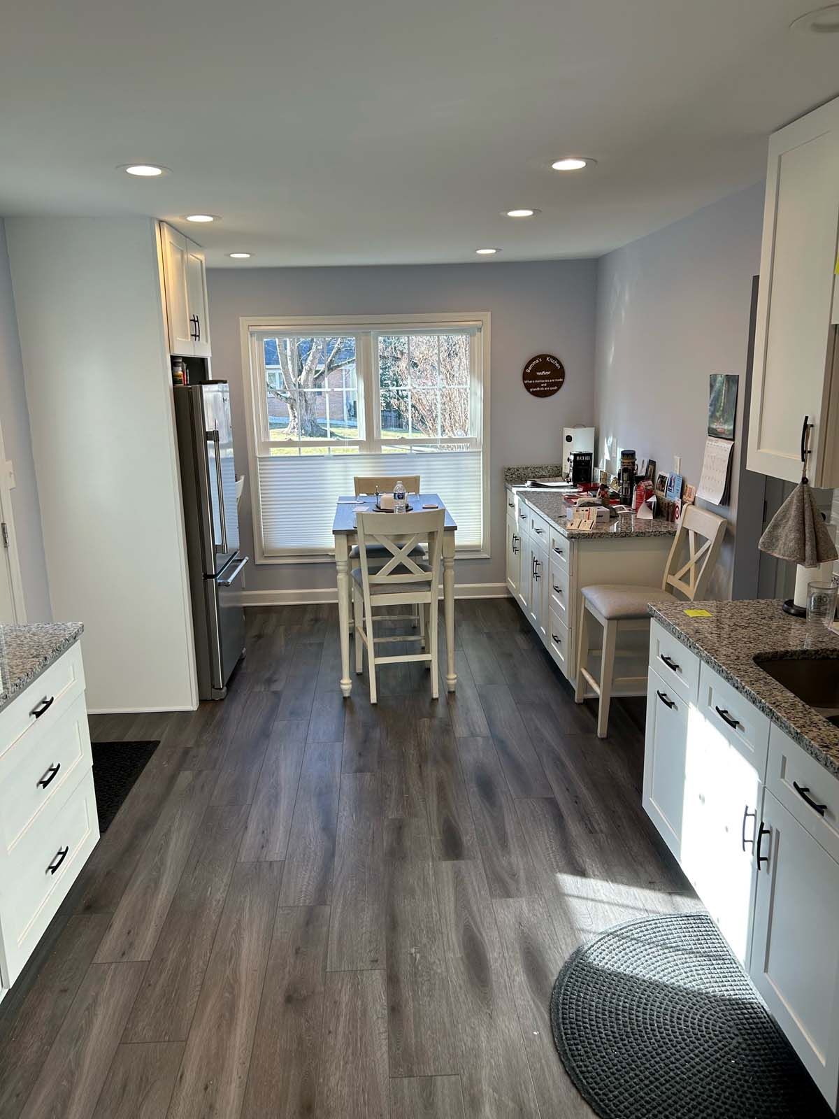 Kitchen with white cabinets, gray floor, and a small table by the window.