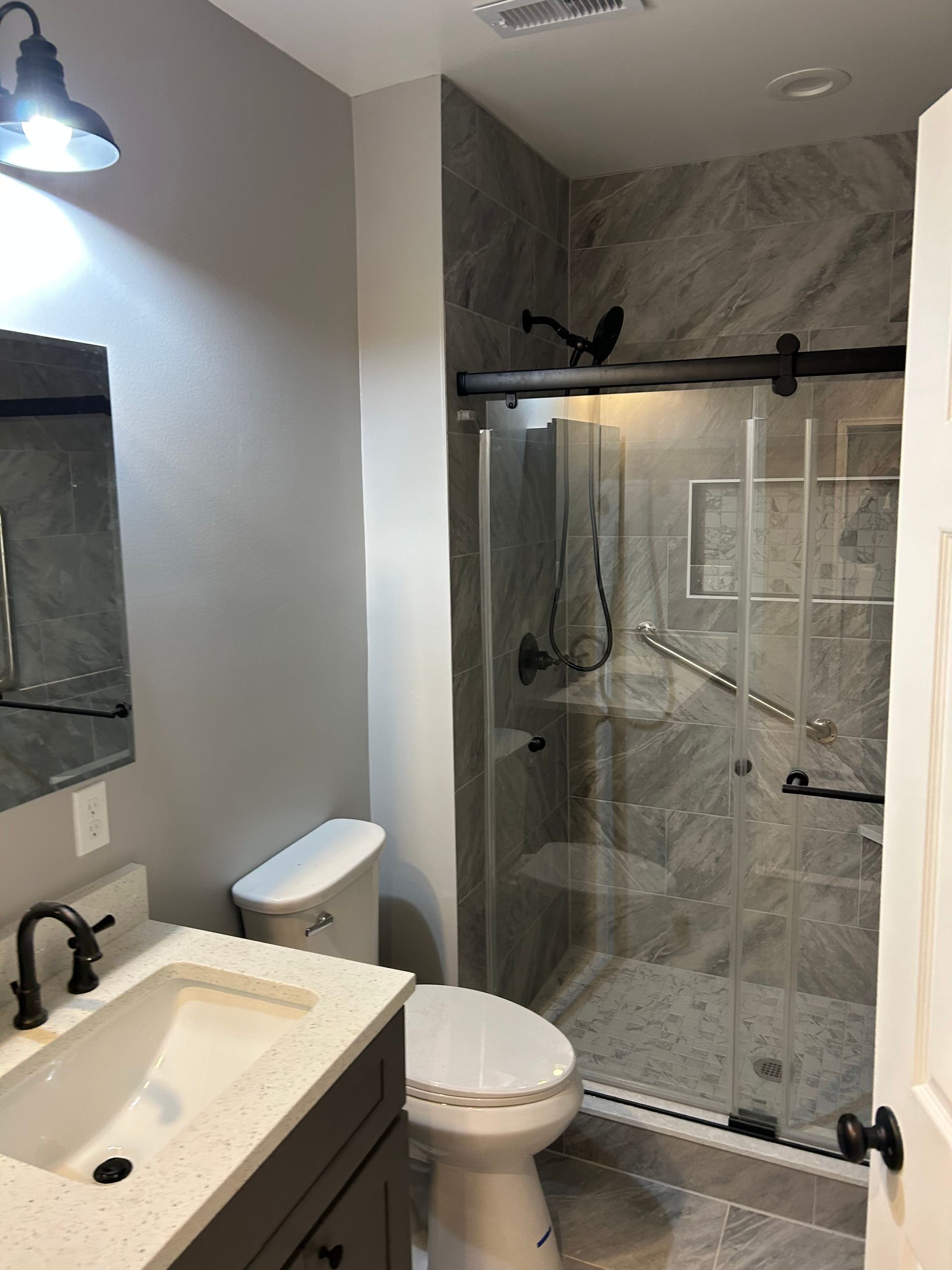 Bathroom with a gray vanity, toilet, and walk-in shower with glass door.