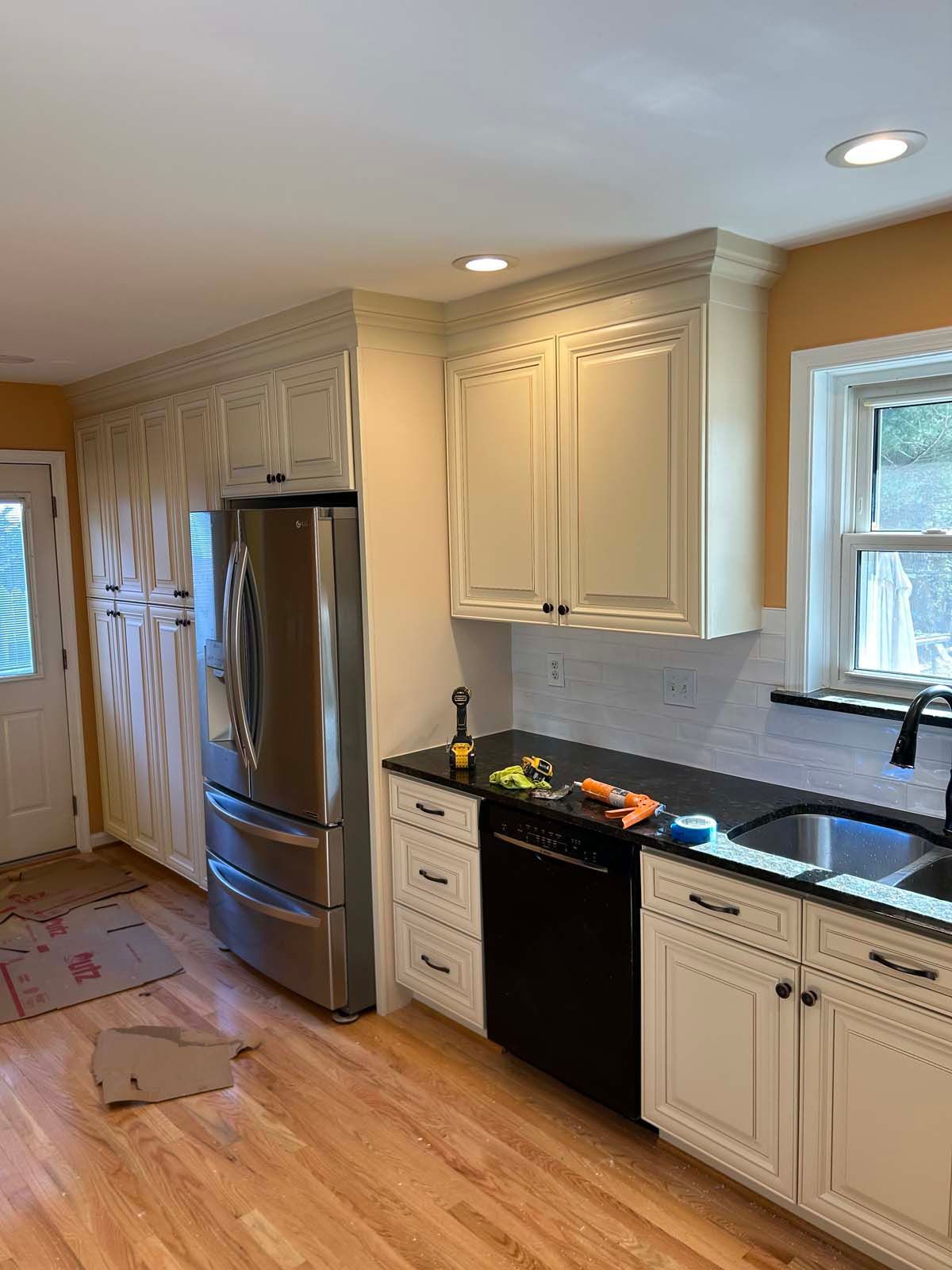 A kitchen with white cabinets, a stainless steel refrigerator, and a black countertop.