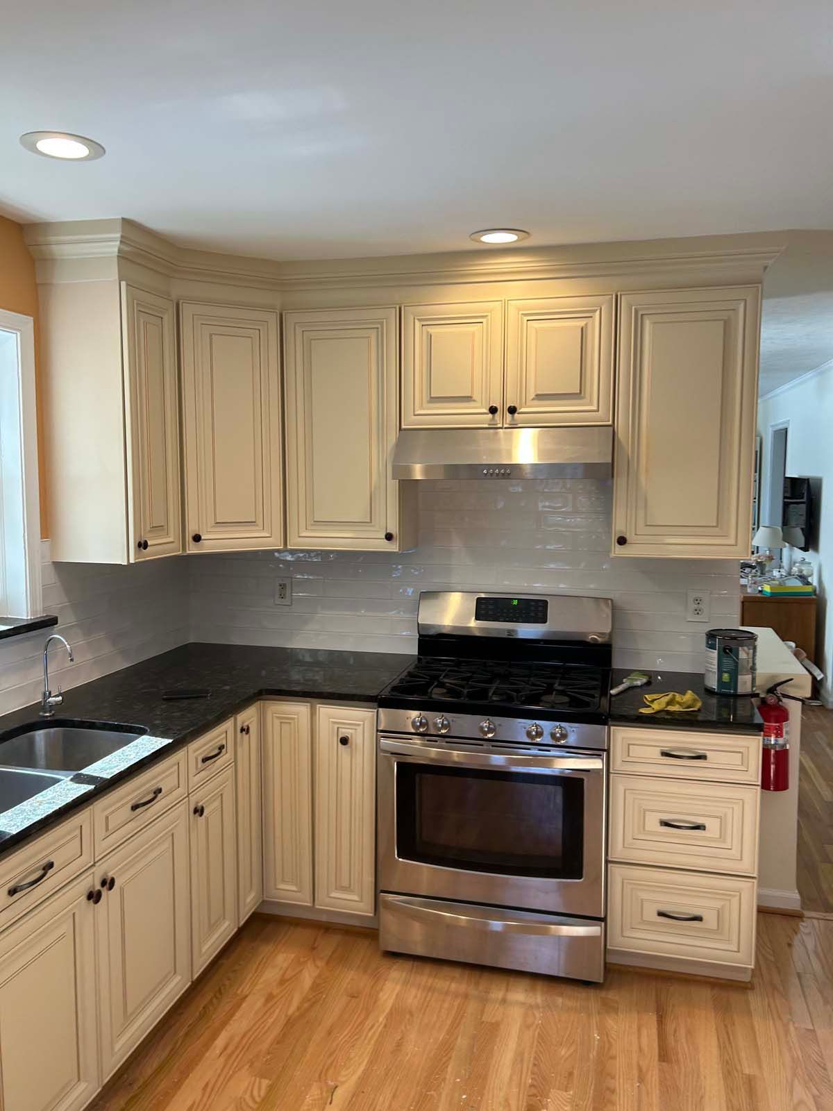 Cream kitchen cabinets with black countertops, stainless steel appliances, and wood flooring.