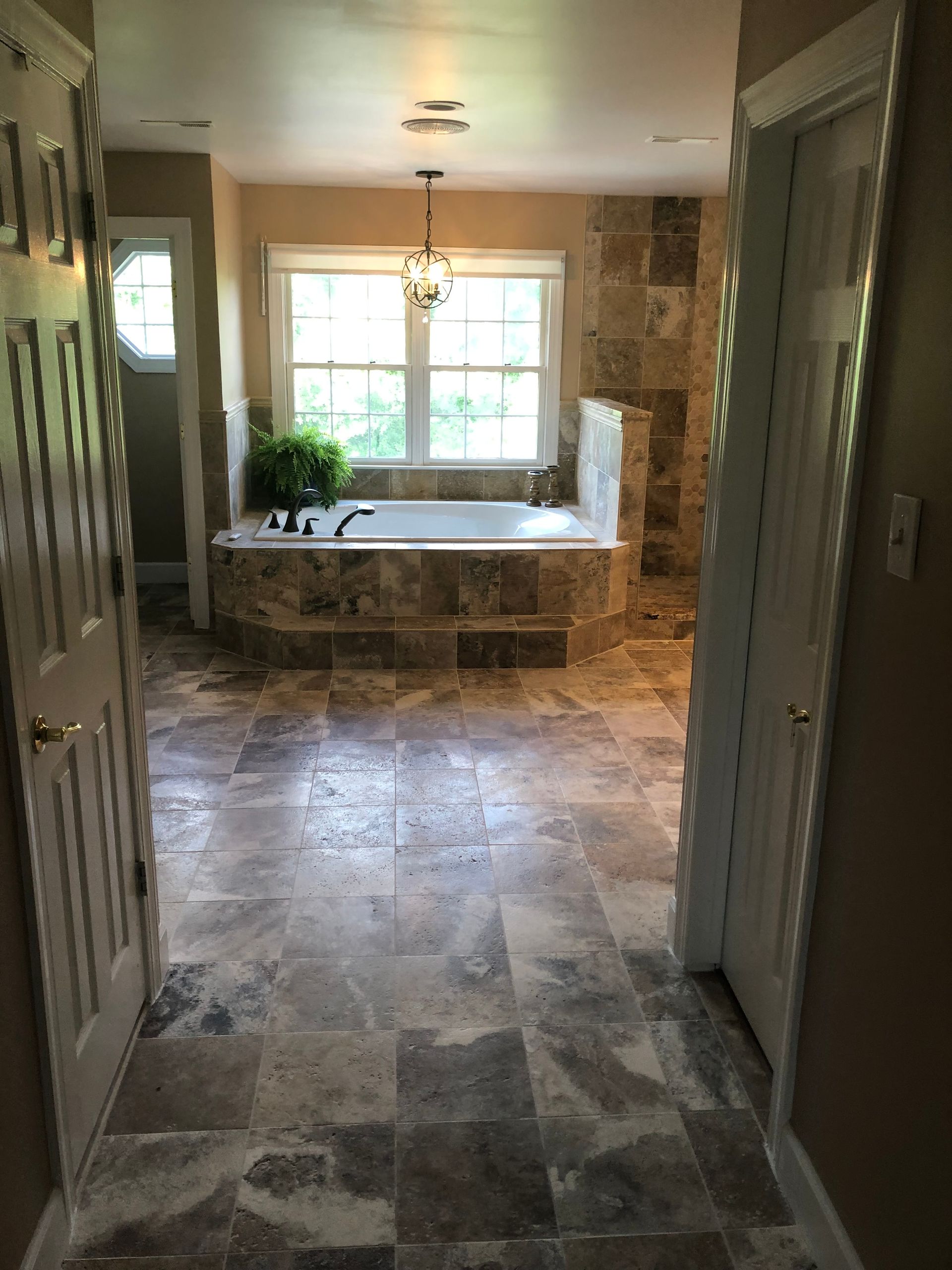 Bathroom with stone tile floors, bathtub, and window.