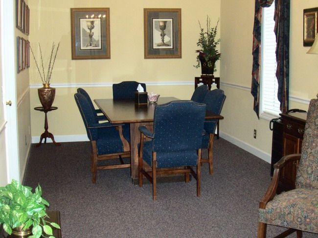 Dining room with dark wood table, blue chairs, floral decor, and two framed pictures.