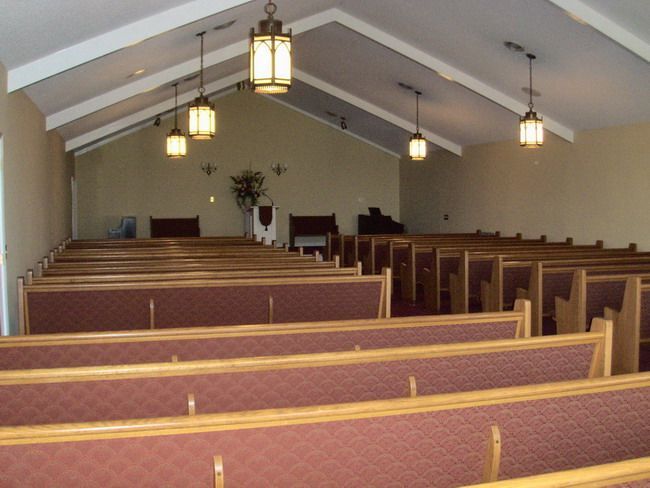 Interior of a church with rows of pews and hanging lights.