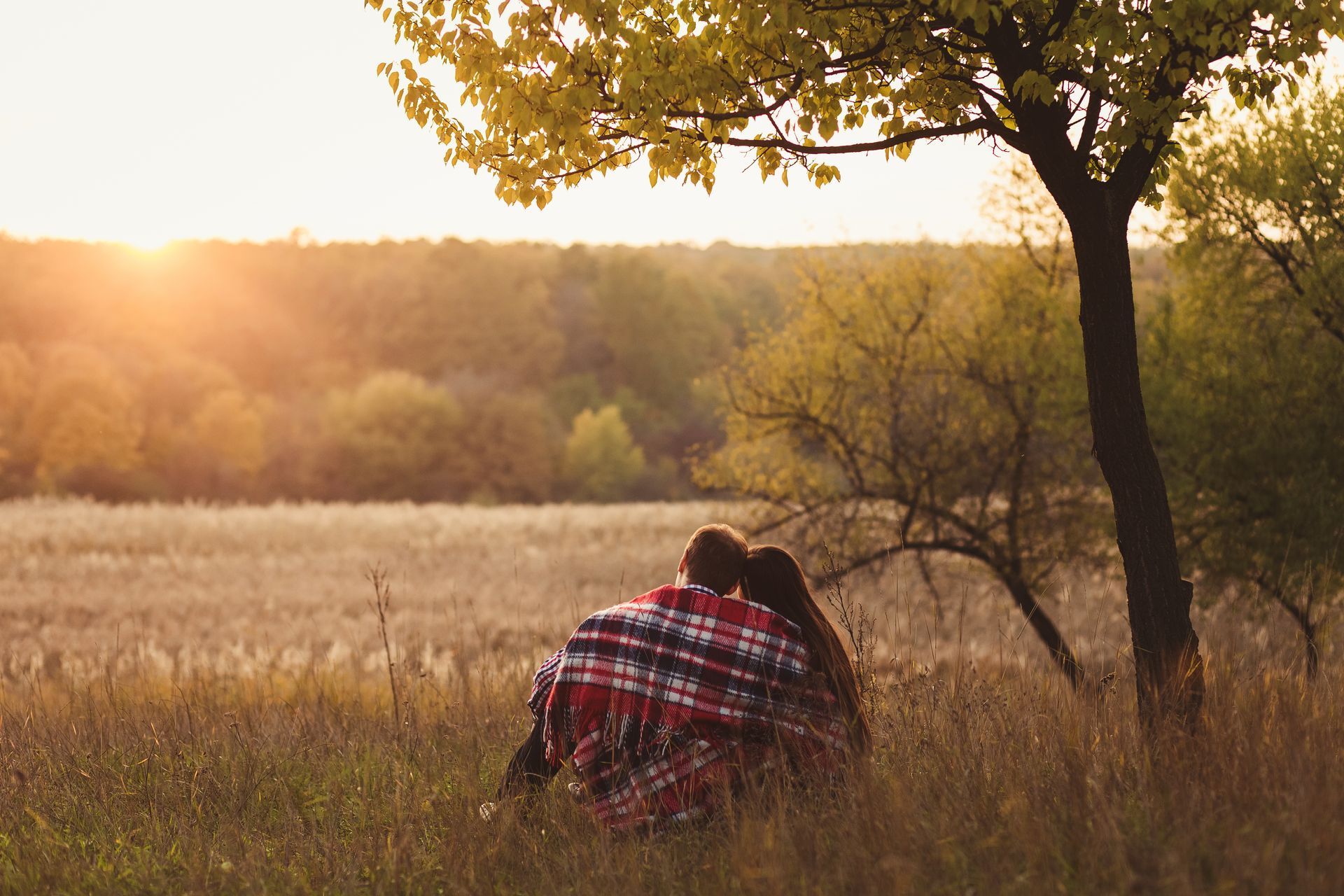 An elderly couple hugging each other on a rooftop at sunset.
