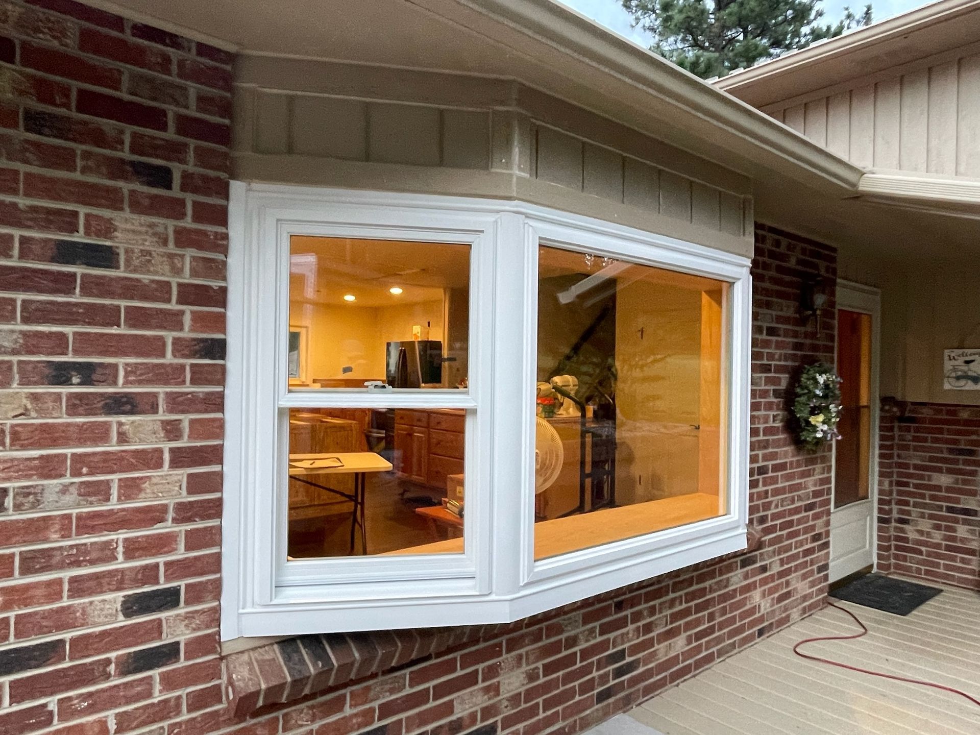 Bay window with white trim in a brick house; interior lights visible.